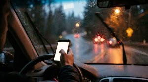 Conductor usando el celular al volante en una carretera lluviosa de Washington, accidente por conductor distraído
